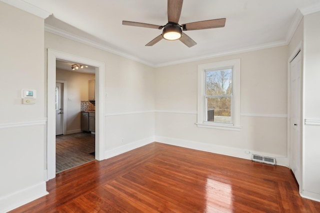 empty room featuring visible vents, ornamental molding, a ceiling fan, wood finished floors, and baseboards