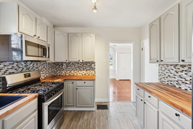 kitchen featuring visible vents, decorative backsplash, wood counters, appliances with stainless steel finishes, and light wood-type flooring