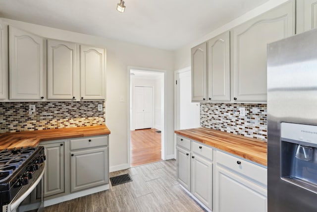 kitchen with butcher block countertops, appliances with stainless steel finishes, and decorative backsplash