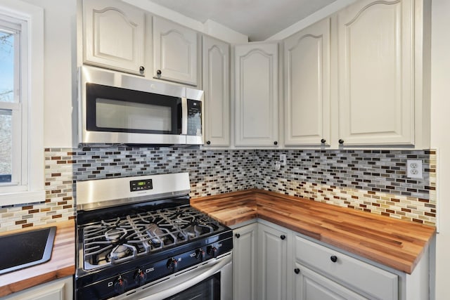 kitchen with stainless steel appliances, tasteful backsplash, and wood counters