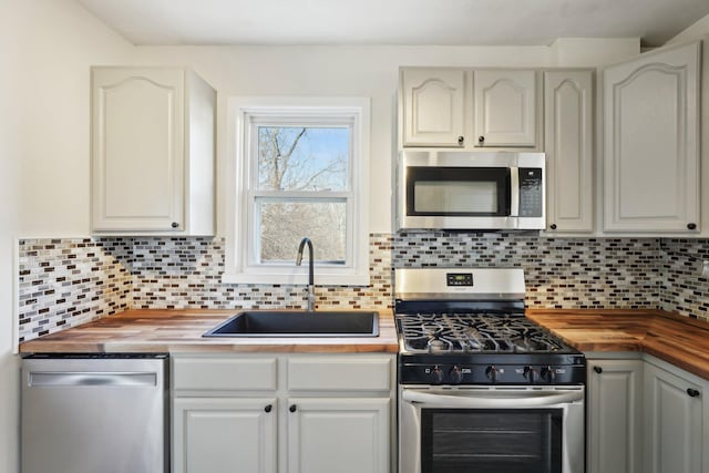 kitchen with butcher block countertops, stainless steel appliances, a sink, and tasteful backsplash