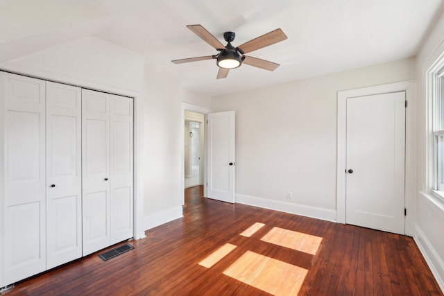 unfurnished bedroom featuring dark wood-type flooring, a closet, visible vents, and baseboards