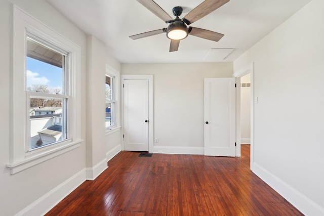 interior space with a ceiling fan, dark wood finished floors, visible vents, and baseboards