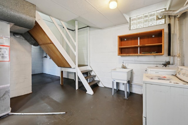 finished basement with concrete block wall, stairs, and washer / clothes dryer