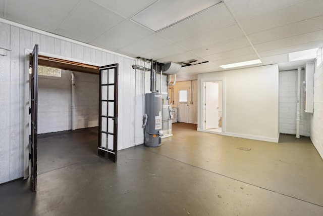 below grade area featuring water heater, wooden walls, and a drop ceiling