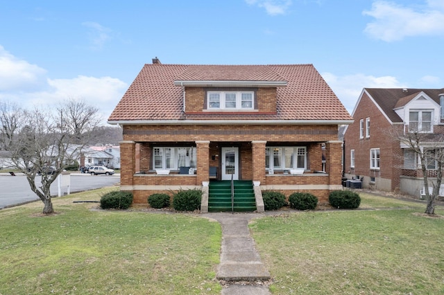 bungalow featuring central AC unit, a porch, a front yard, and brick siding