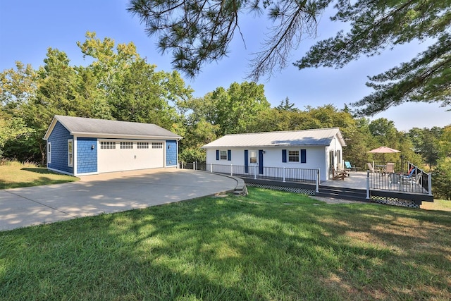 view of front of home with a deck, a detached garage, a front lawn, and an outbuilding