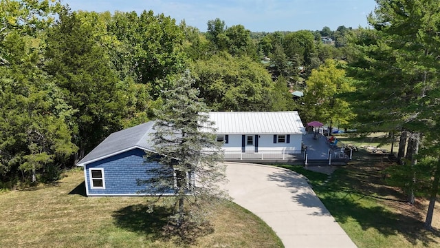 view of front of property featuring a wooded view, a front lawn, and concrete driveway