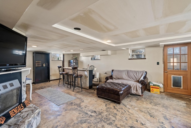 living area with a fireplace with raised hearth and a bar