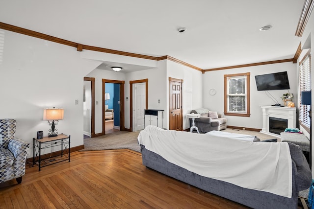 bedroom with ornamental molding, a fireplace, baseboards, and wood finished floors