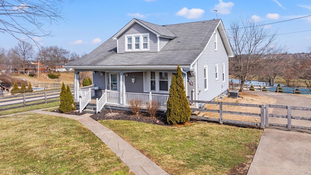 bungalow-style home featuring a porch, a fenced front yard, central AC unit, and a front lawn