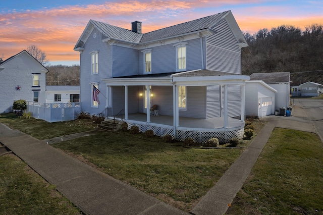 view of front facade featuring a porch, metal roof, an outbuilding, a standing seam roof, and a front lawn