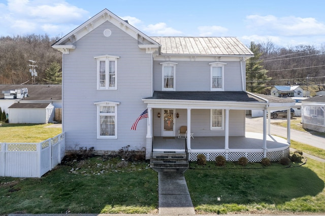 view of front of house featuring a front yard, covered porch, fence, and metal roof