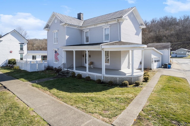 view of front of home featuring an outbuilding, covered porch, a standing seam roof, metal roof, and a front lawn