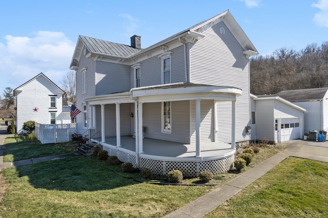 back of property featuring a lawn, metal roof, a standing seam roof, an outdoor structure, and a porch