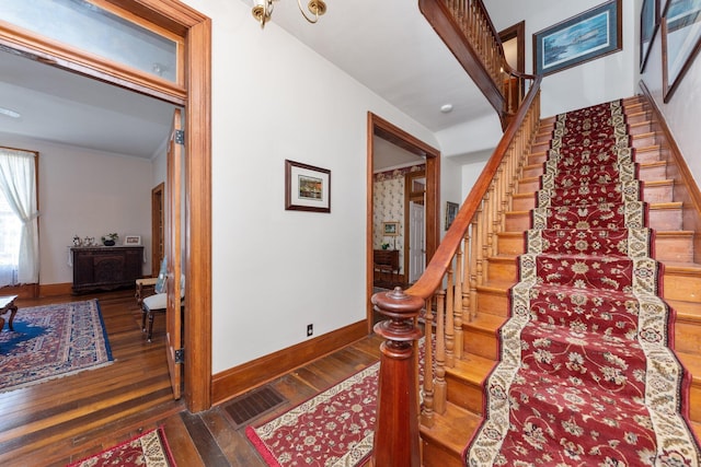 stairway featuring hardwood / wood-style floors, visible vents, and baseboards