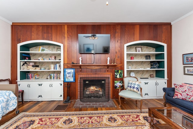 living area featuring ornamental molding, a fireplace, wood finished floors, and built in features