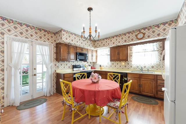 dining room with light wood-type flooring, french doors, a notable chandelier, and wallpapered walls