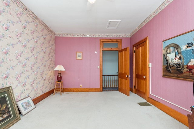 carpeted empty room featuring visible vents, baseboards, and wallpapered walls