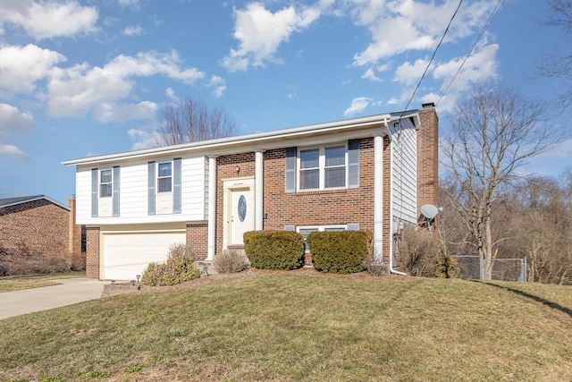 split foyer home with a garage, brick siding, concrete driveway, a chimney, and a front yard