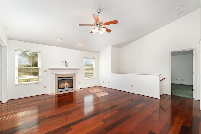 unfurnished living room with high vaulted ceiling, a tiled fireplace, wood finished floors, baseboards, and ceiling fan