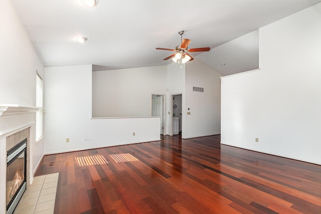 unfurnished living room with visible vents, a tile fireplace, light wood-style floors, high vaulted ceiling, and a ceiling fan