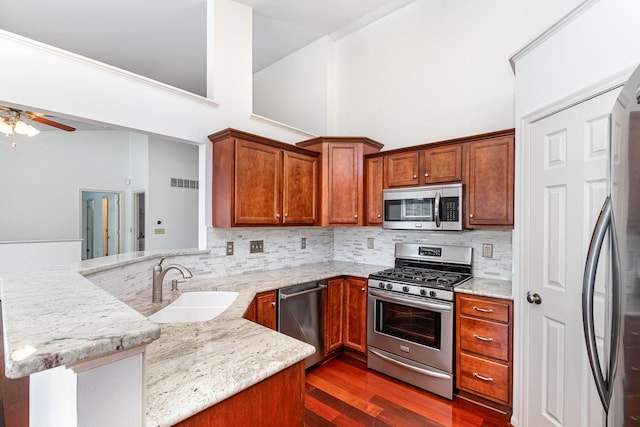 kitchen featuring visible vents, light stone countertops, appliances with stainless steel finishes, a peninsula, and a sink