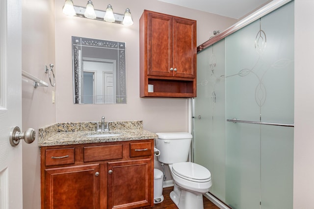 bathroom featuring a shower stall, toilet, and vanity