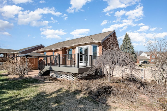 back of property with a lawn, fence, and a wooden deck