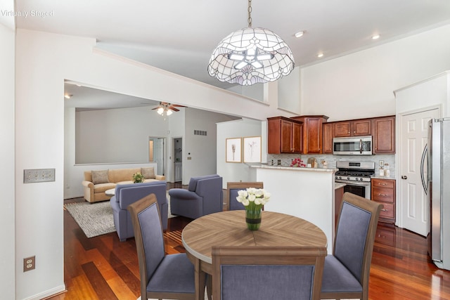 dining space featuring a high ceiling, dark wood-style floors, visible vents, and ceiling fan