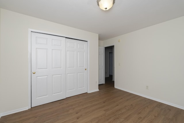 unfurnished bedroom featuring a closet, baseboards, and wood finished floors