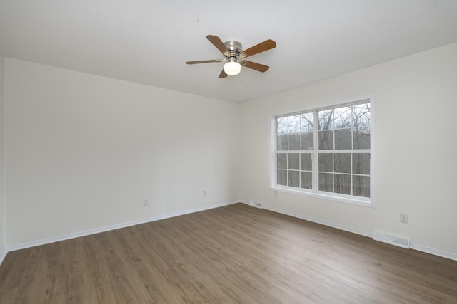 spare room with ceiling fan, wood finished floors, visible vents, and baseboards