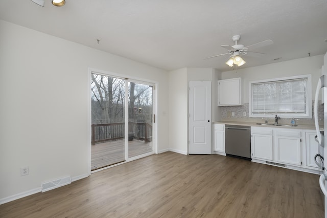 kitchen featuring a sink, visible vents, white cabinetry, light wood-type flooring, and dishwasher