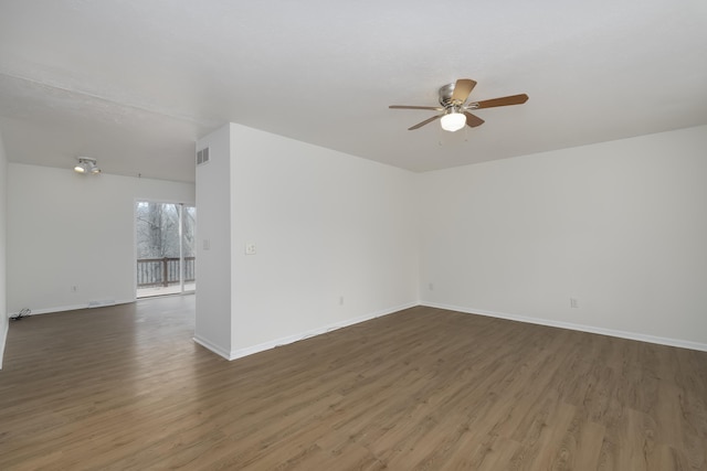 spare room with a ceiling fan, visible vents, baseboards, and wood finished floors