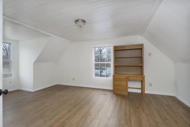 additional living space with lofted ceiling, wood finished floors, visible vents, and baseboards