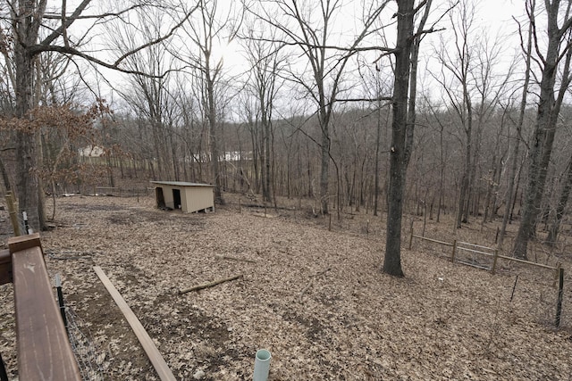 view of yard featuring a storage unit, a wooded view, and an outbuilding