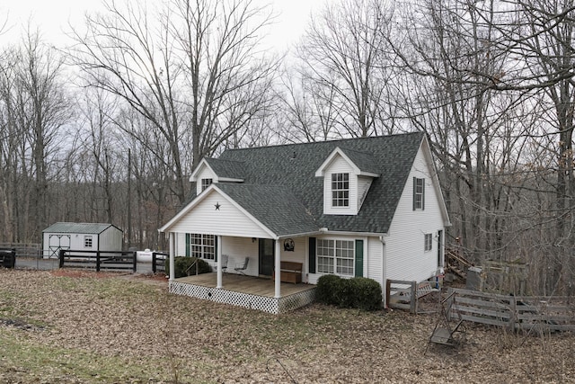 view of front of property featuring a patio area, roof with shingles, fence, and an outdoor structure