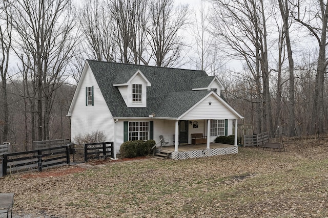 view of front of house with covered porch, fence, and roof with shingles