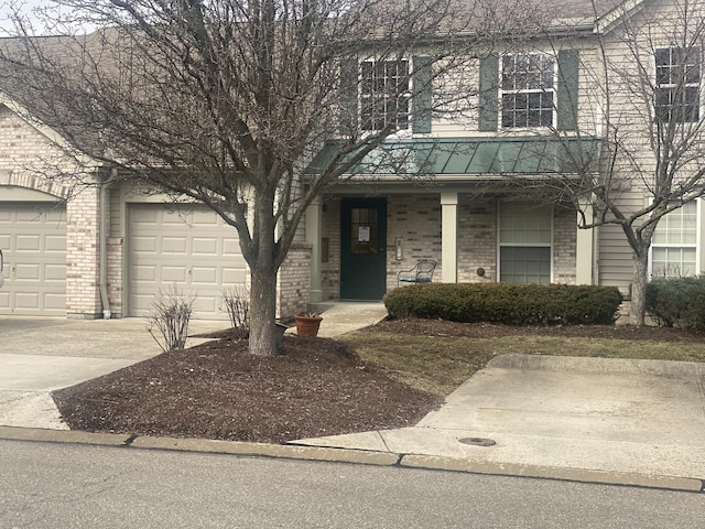 view of front of house with an attached garage, a porch, concrete driveway, and brick siding