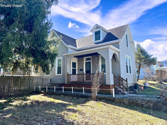 view of front of home featuring a porch, a shingled roof, and fence