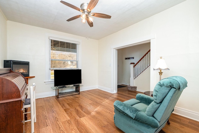 living area with baseboards, light wood finished floors, and stairs