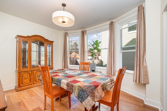 dining room featuring light wood finished floors and baseboards