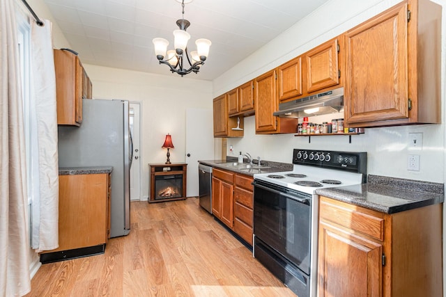 kitchen featuring appliances with stainless steel finishes, dark countertops, a sink, and under cabinet range hood