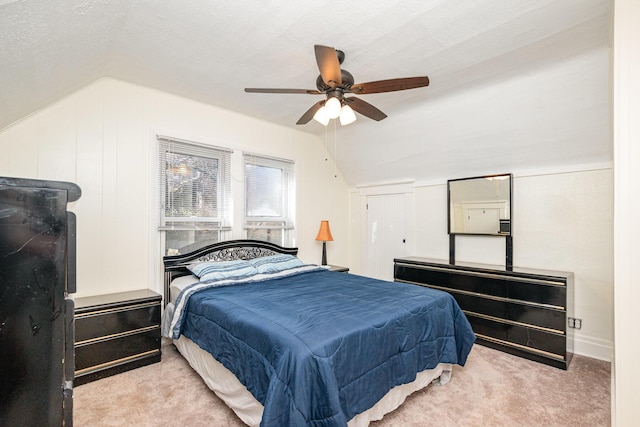 bedroom featuring ceiling fan, carpet, vaulted ceiling, and a textured ceiling