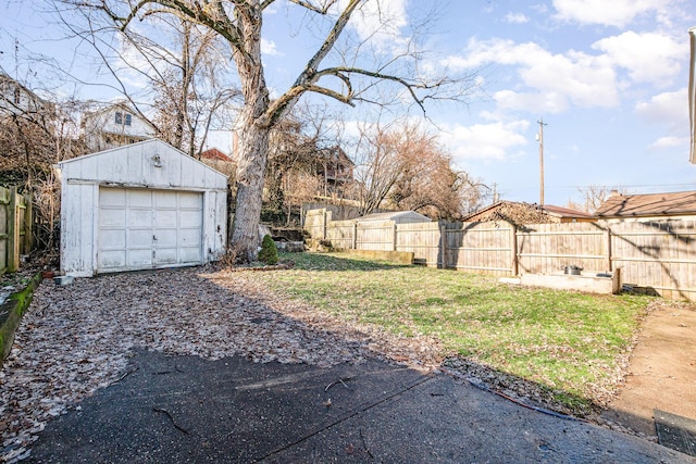 view of yard with a garage, driveway, an outdoor structure, and fence