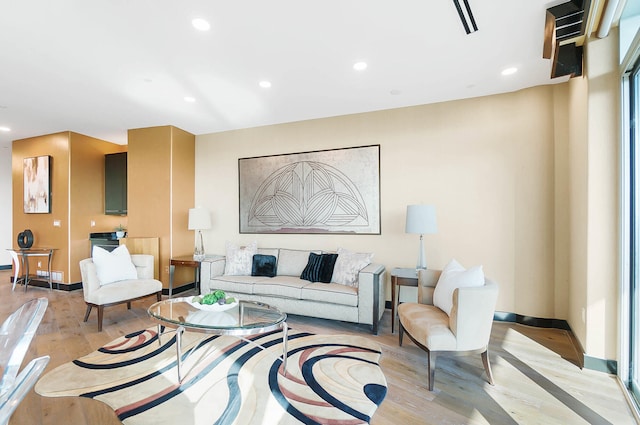 living room with baseboards, light wood-type flooring, and recessed lighting