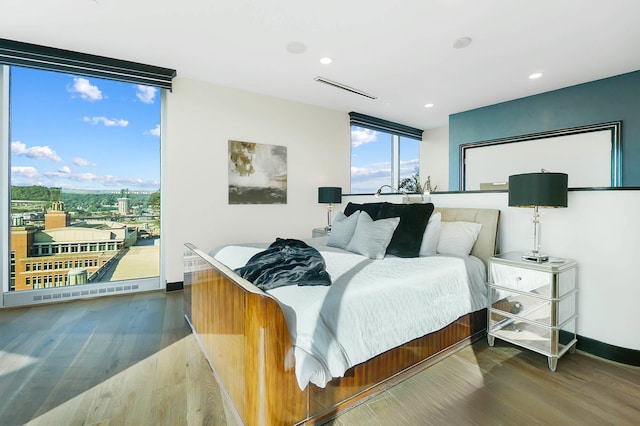 bedroom featuring baseboards, a wall of windows, and wood finished floors