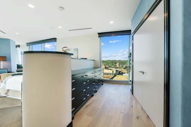 hall featuring a wall of windows, light wood-type flooring, and recessed lighting