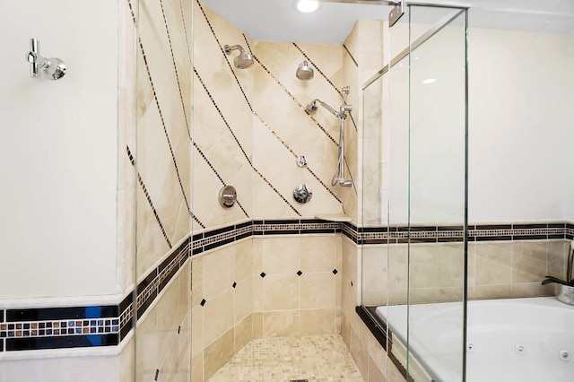 bathroom featuring a tub with jets and a tile shower