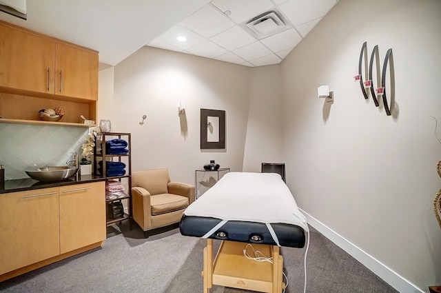 interior space featuring carpet, visible vents, a drop ceiling, and baseboards